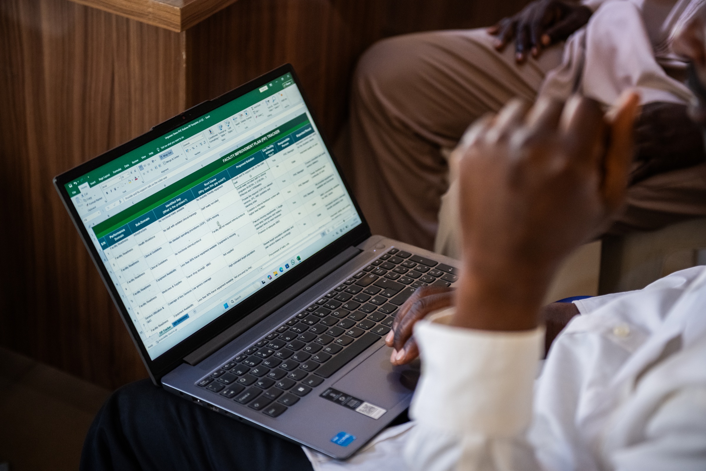 Health workers reviewing a facility improvement tracker on a laptop