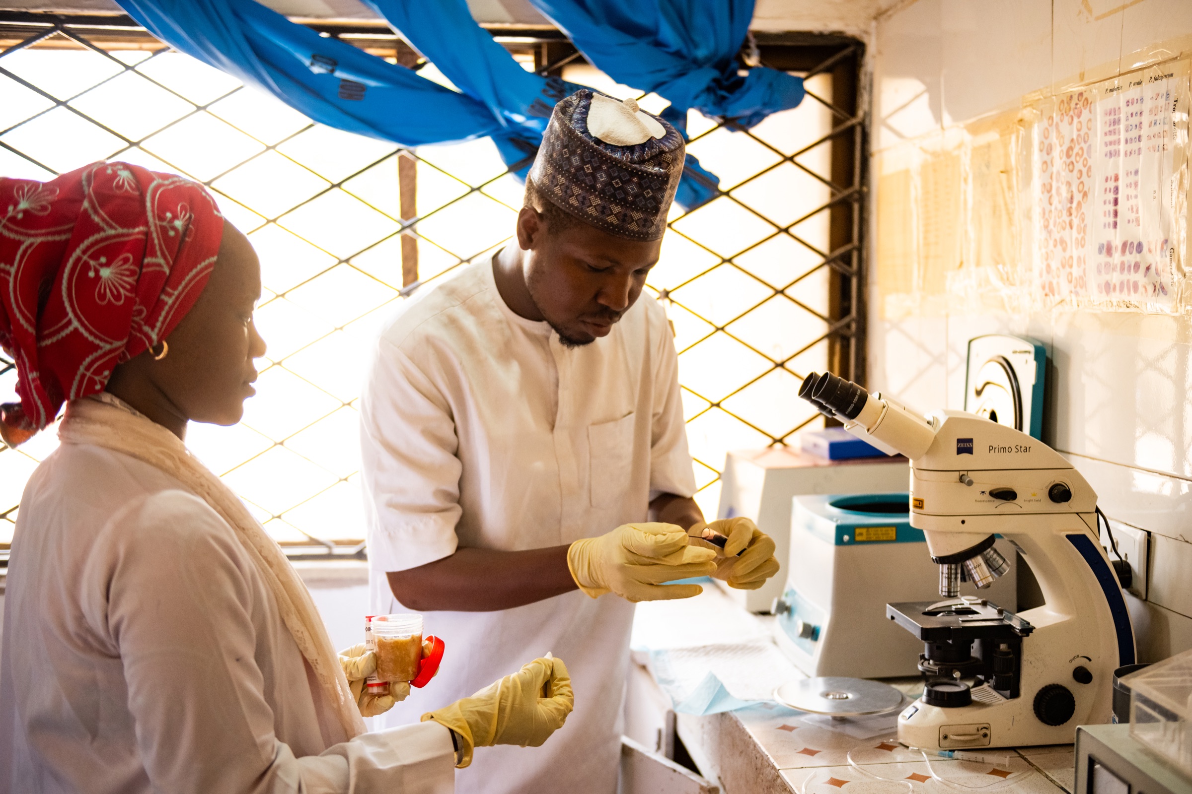 Health workers preparing a sample beside a microscope